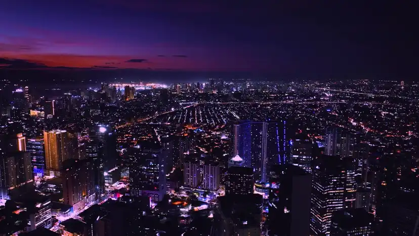 Aerial night view of the Metro Manila skyline at sunset, city lights stretching to the horizon.